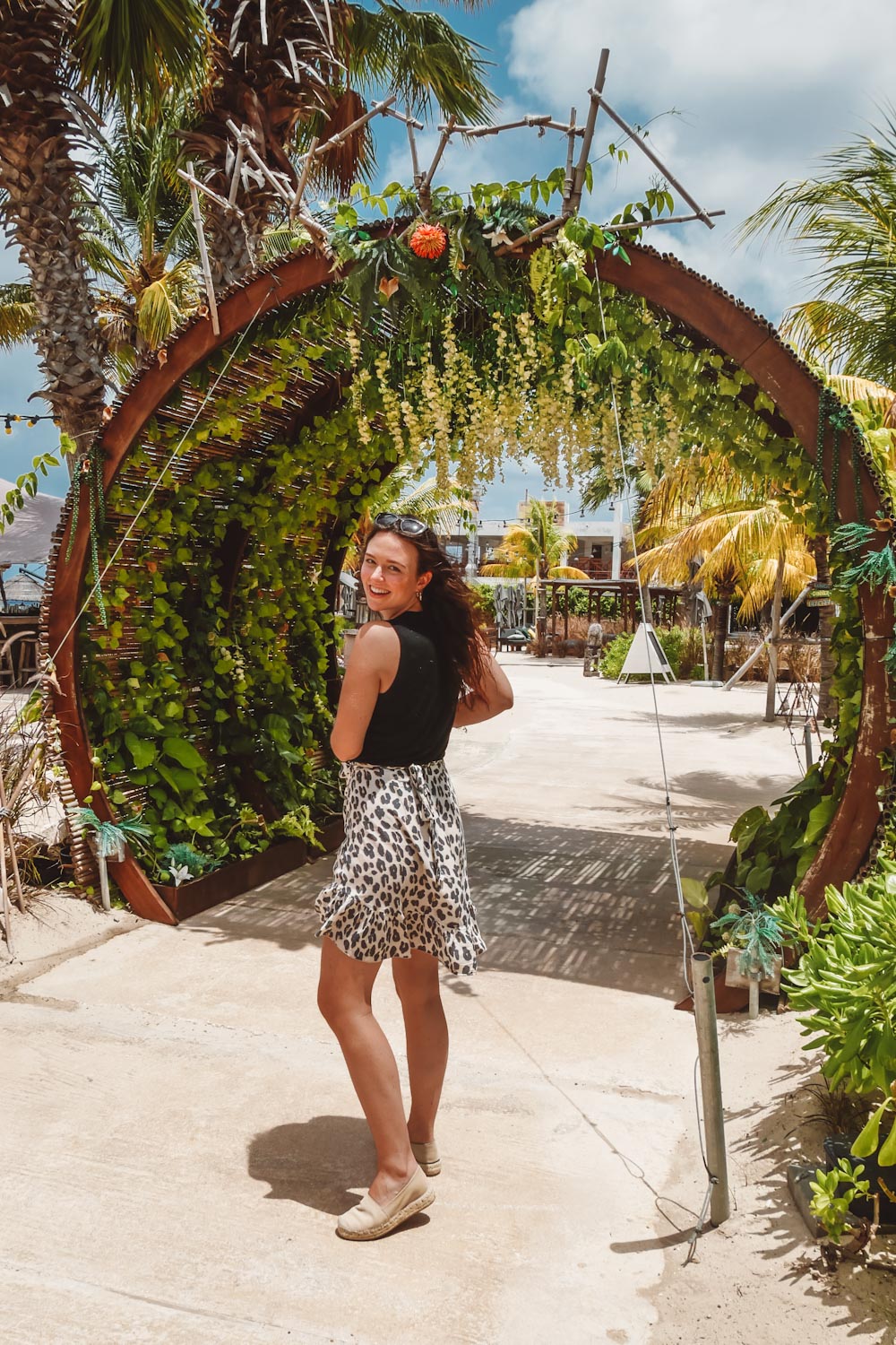 Rachel die onder de toegangspoort van Mood Beach Curaçao doorloopt